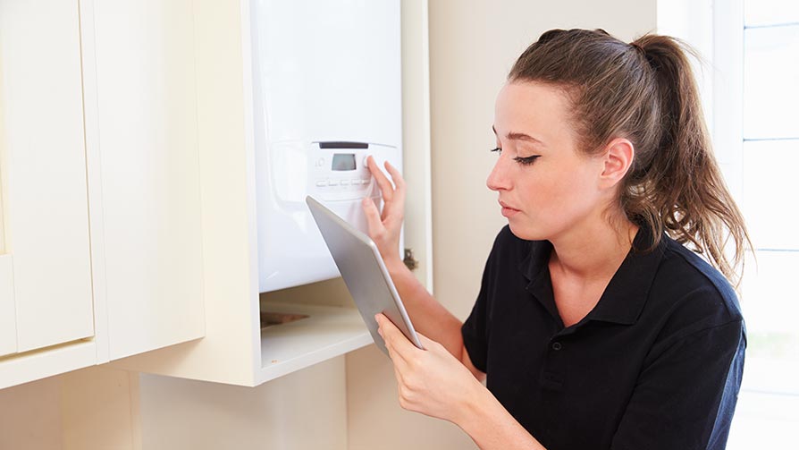 Female technician servicing a new boiler using a tablet computer