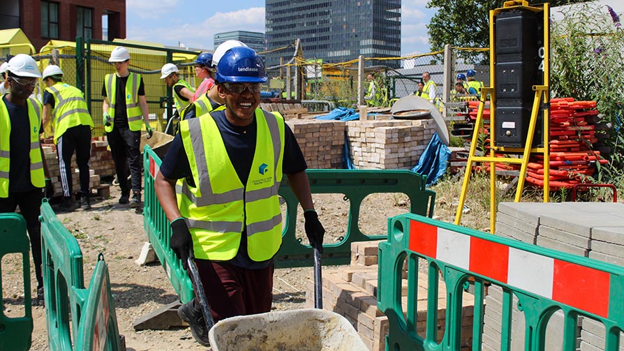 Young person using a wheelbarrow on a building site - Construction Youth Trust Young person using a wheelbarrow on a building site - Construction Youth Trust