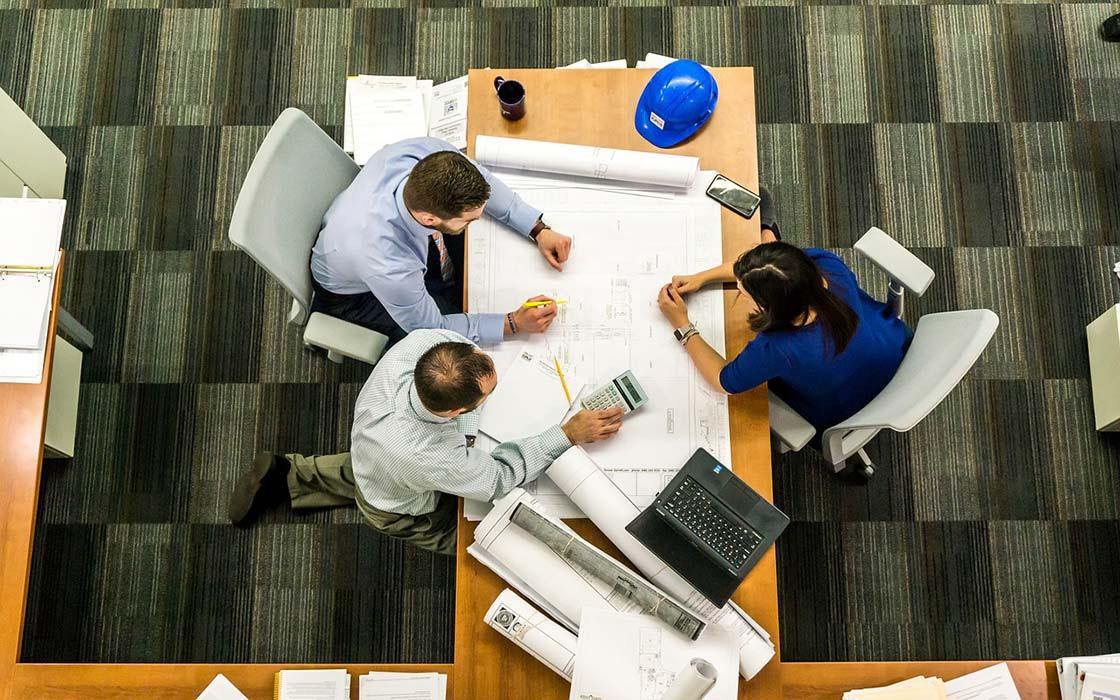 Overhead view of architects and industry professionals working on blueprints