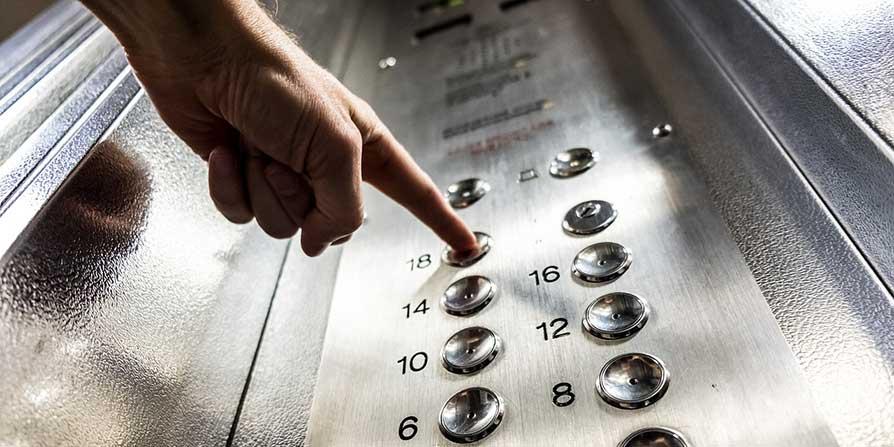 View of a persons finger on lift buttons