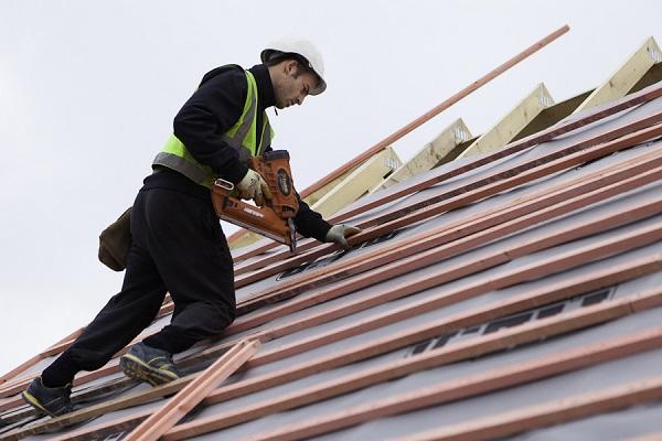 Image of a roofer weatherproofing a roof by working on battens