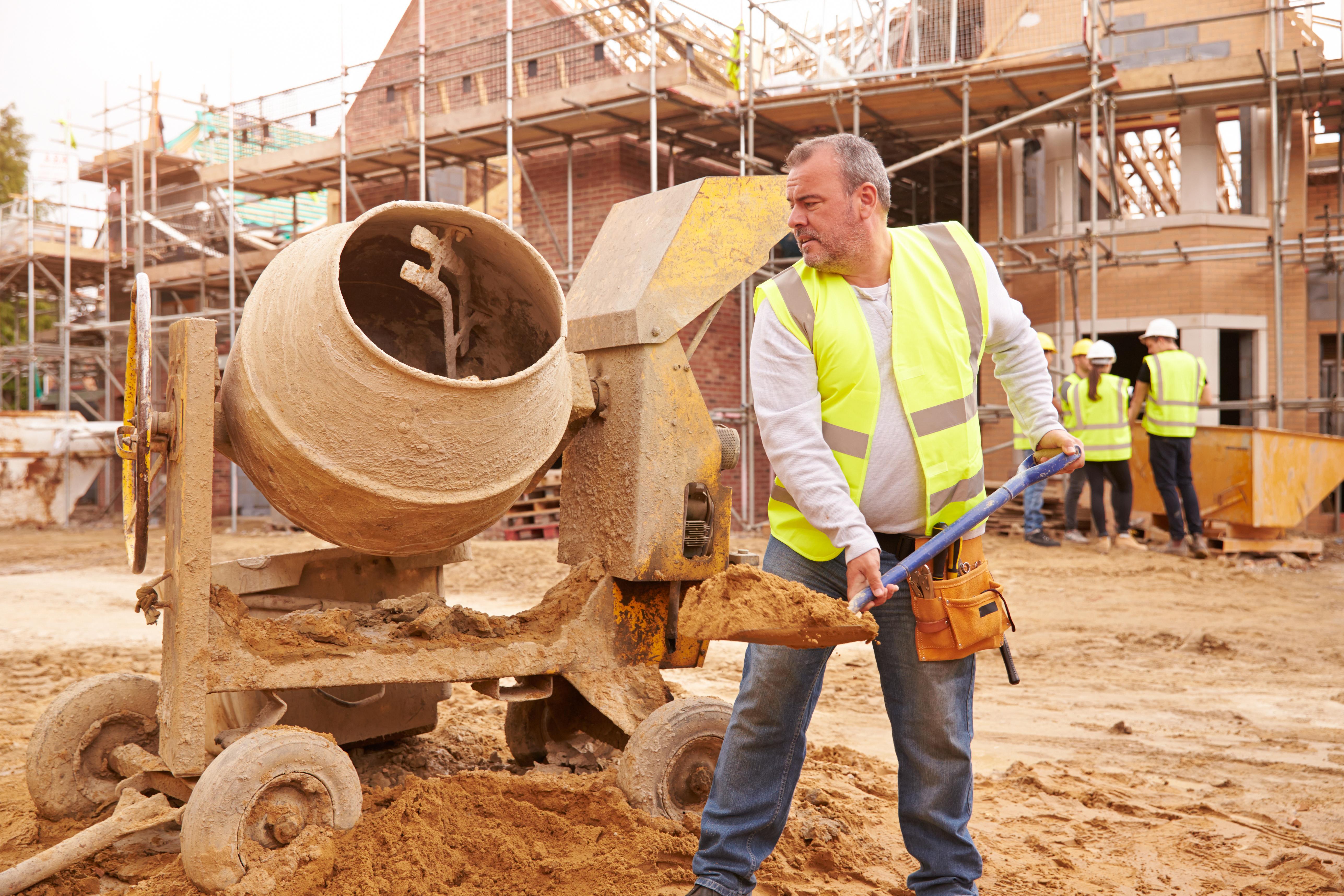 Builder at construction site with cement mixer